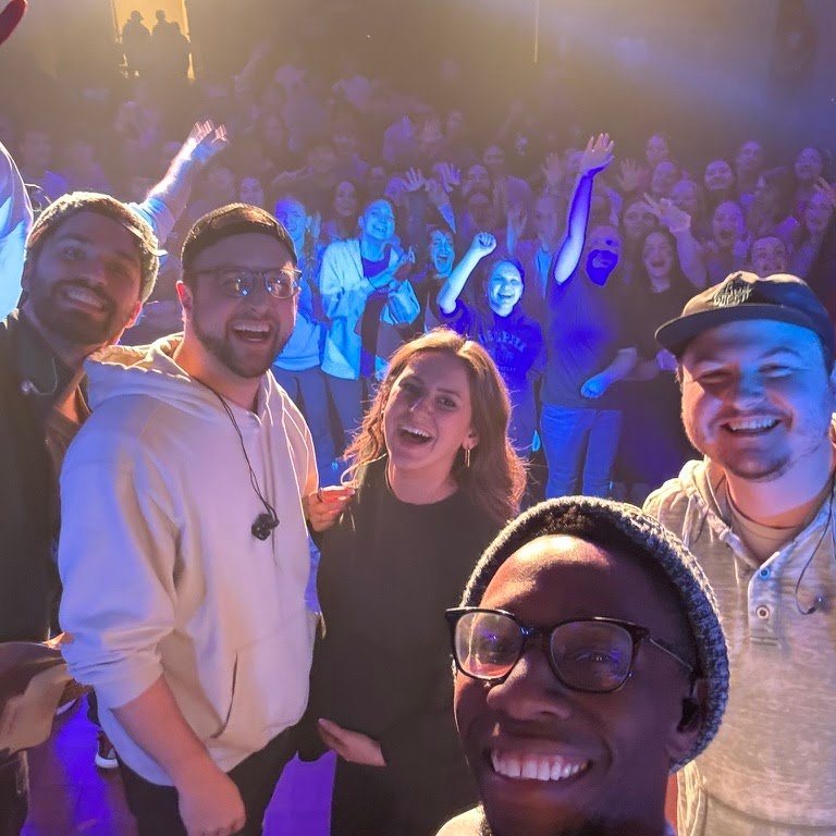 Jon taking a group selfie with friends in front of a crowd at a worship event